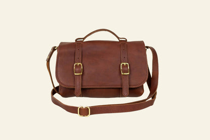 Brown leather satchel bag with gold buckles on a white background