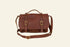 Brown leather satchel bag with gold buckles on a white background