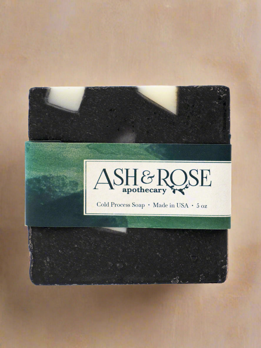 Bar of soap with a label for Ash &amp; Rose apothecary on a white background
