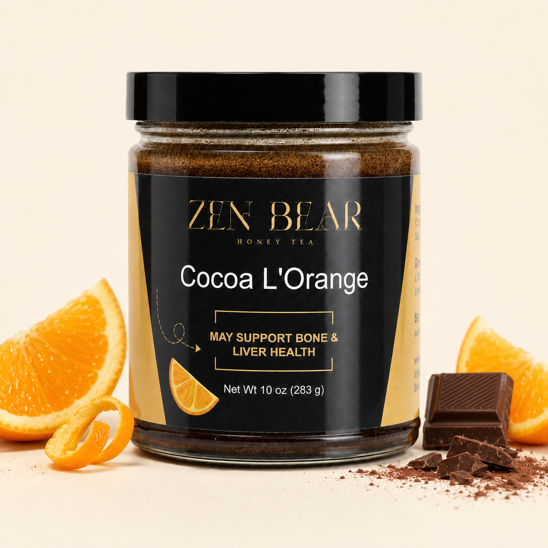 A jar of Zen Bear Cocoa L-Orange honey tea blend, styled with orange slices, cocoa powder, and chocolate chunks on a light beige background.