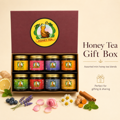 A Tees&amp;Bee Honey Tea gift box set displayed on a warm cream background. The open burgundy box contains eight mini jars of assorted honey tea blends with gold lids.