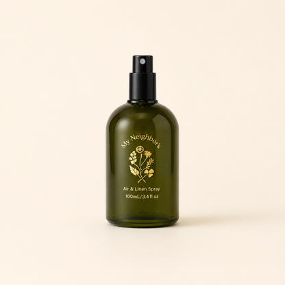 An olive green glass spray bottle with a black pump dispenser, featuring gold foil branding that reads &