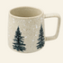 A speckled beige ceramic mug with a rounded shape, a large handle, and two dark green pine tree illustrations on the front, set against a solid cream background.