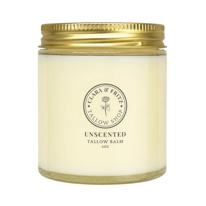 A 4oz jar candle from Clara &amp; Frizz Tallow Shop, Unscented Tallow Balm. The candle is in a clear glass jar filled with creamy off-white wax, featuring a metallic gold screw-on lid and a black printed logo on the front.