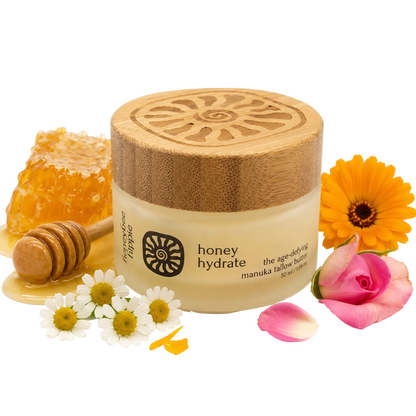 Jar of honey hydrate with wooden lid, honeycomb, flowers, and honey dipper on a white background