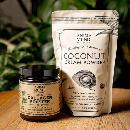 Anima Mundi Coconut Cream Powder and Collagen Booster on a wooden surface with a green leafy background