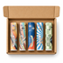 Five lip balm tubes in assorted flavors arranged inside an open brown cardboard box on a white background. The tubes feature colorful retro-style labels with text including Vanilla Bean, Pink Collar, Cotton Candy, Upside Down, and Classic Chocolate.