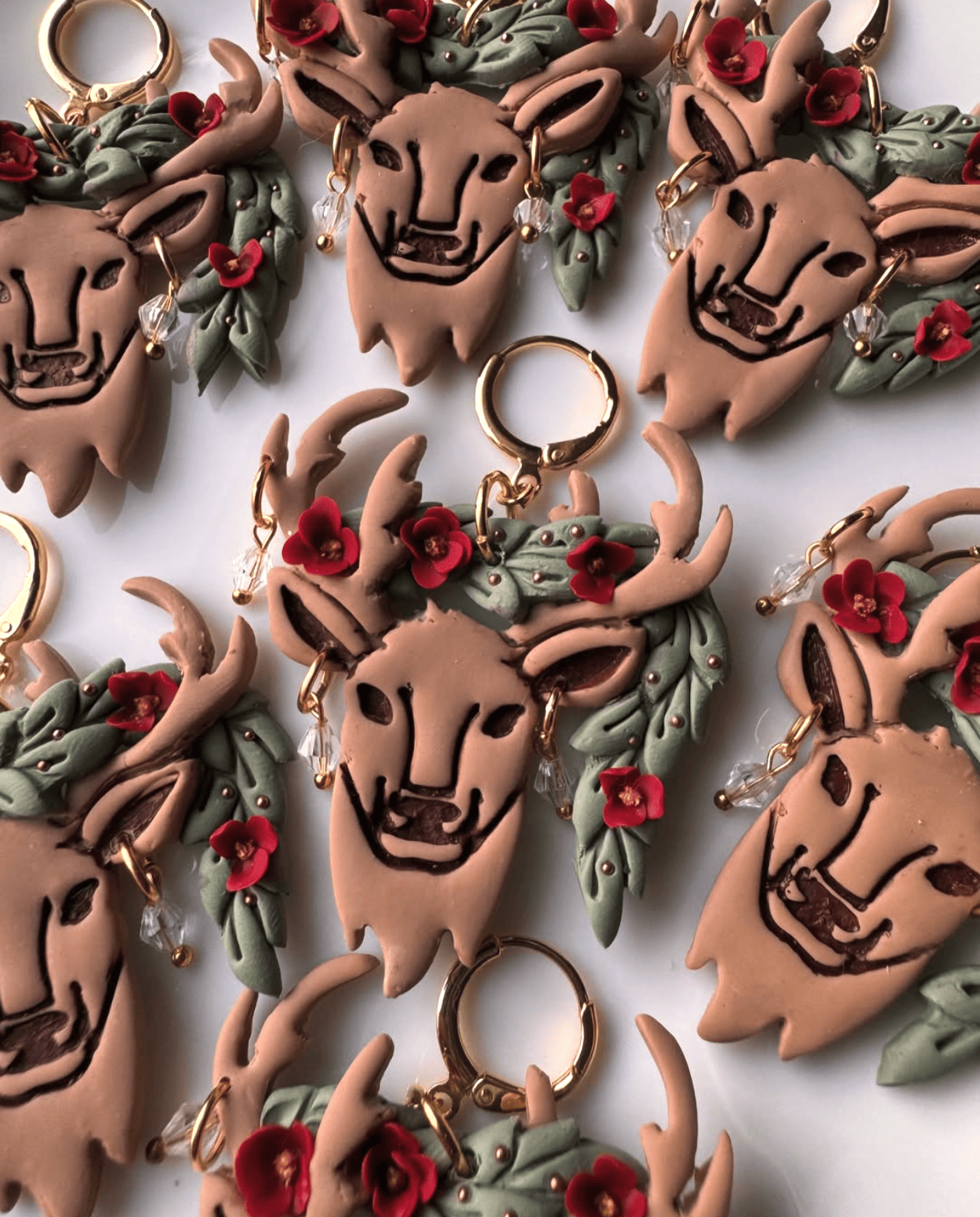 Collection of deer-shaped earrings with floral decorations on a white background