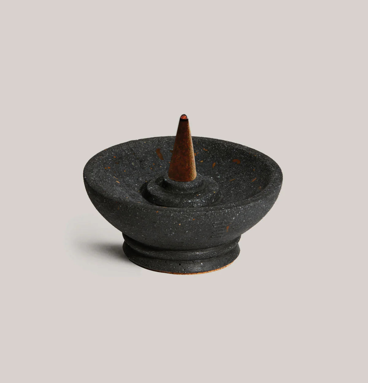 Black ceramic incense burner with a single cone on a light gray background