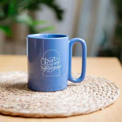 A blue ceramic mug with a white printed graphic reading &