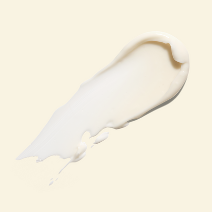 A thick, creamy white cosmetic smear on a solid pale beige background.