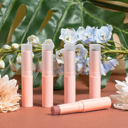 Set of lip balms on a brown surface with flowers in the background