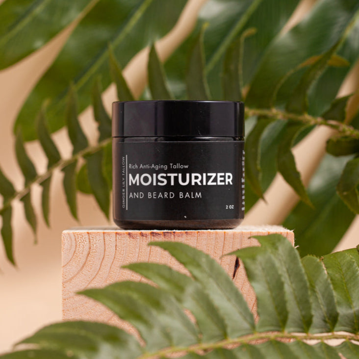 Black jar of moisturizer and beard balm on a wooden block with green leaves in the background
