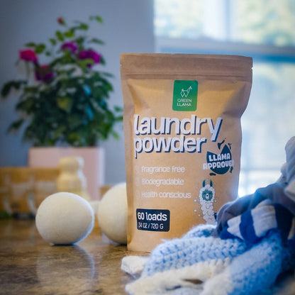 Package of laundry powder with detergent balls on a wooden surface, plant and window in the background