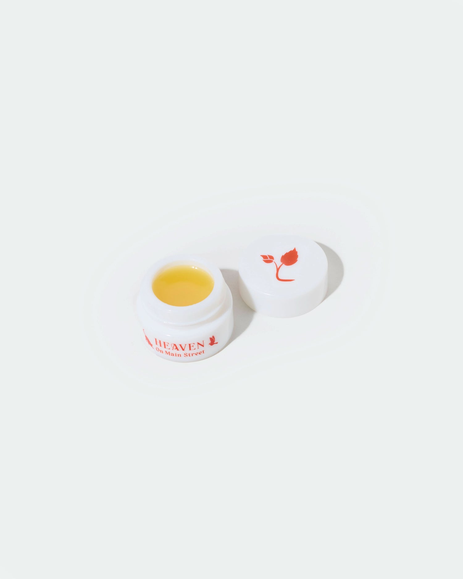 Small jar of cream with a white lid on a white background