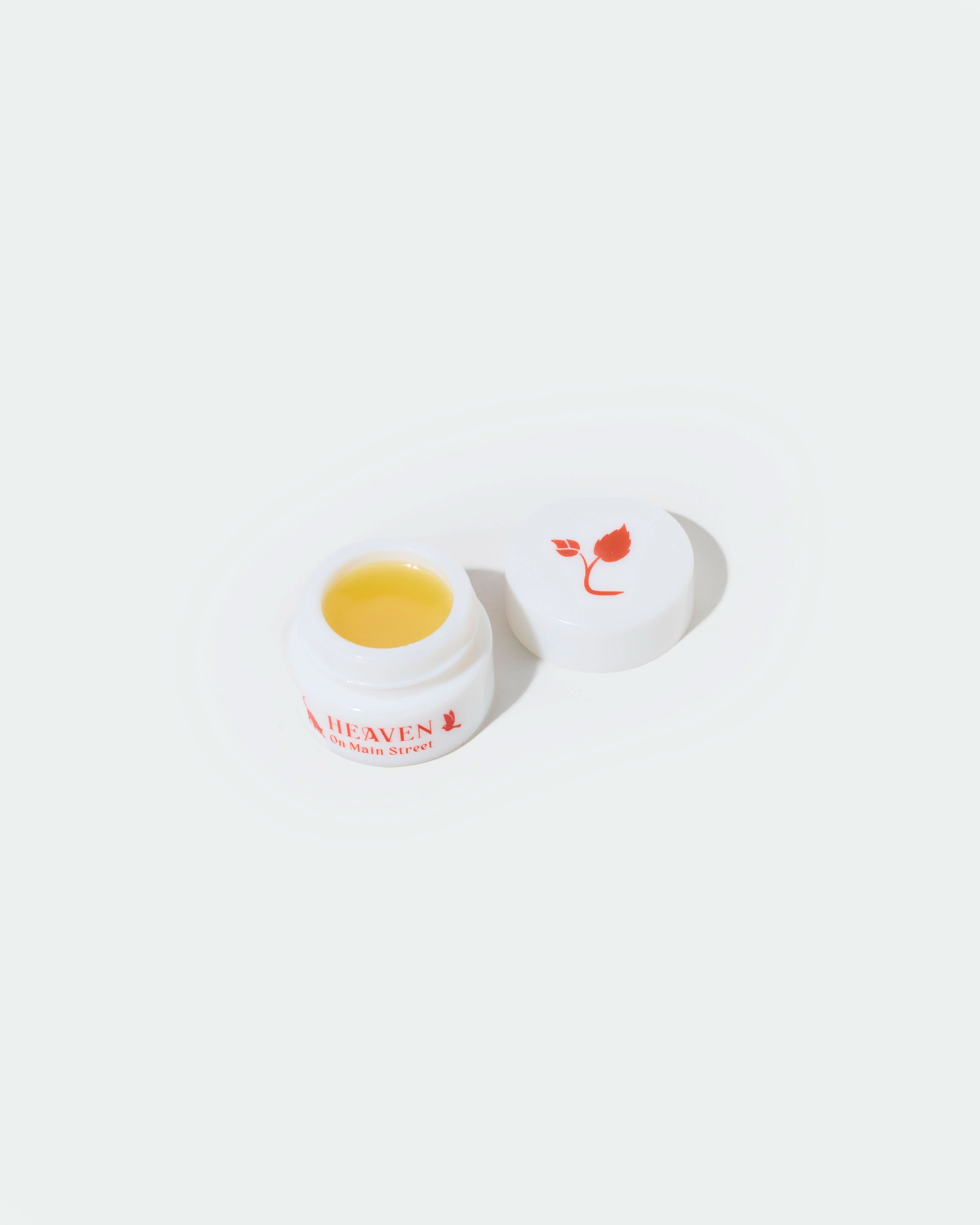 Small jar of cream with a white lid on a white background