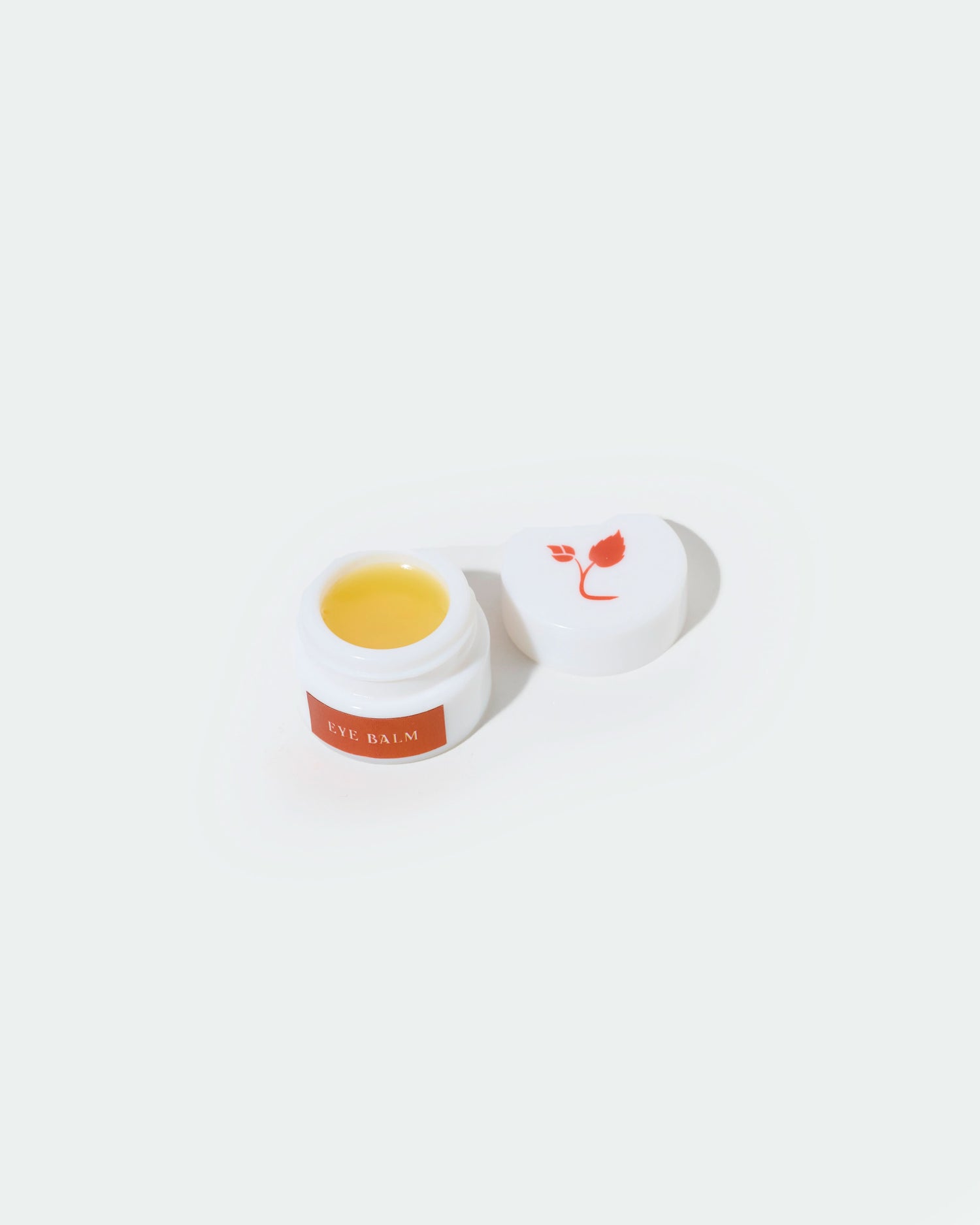 Small jar of balm with a white lid on a white background