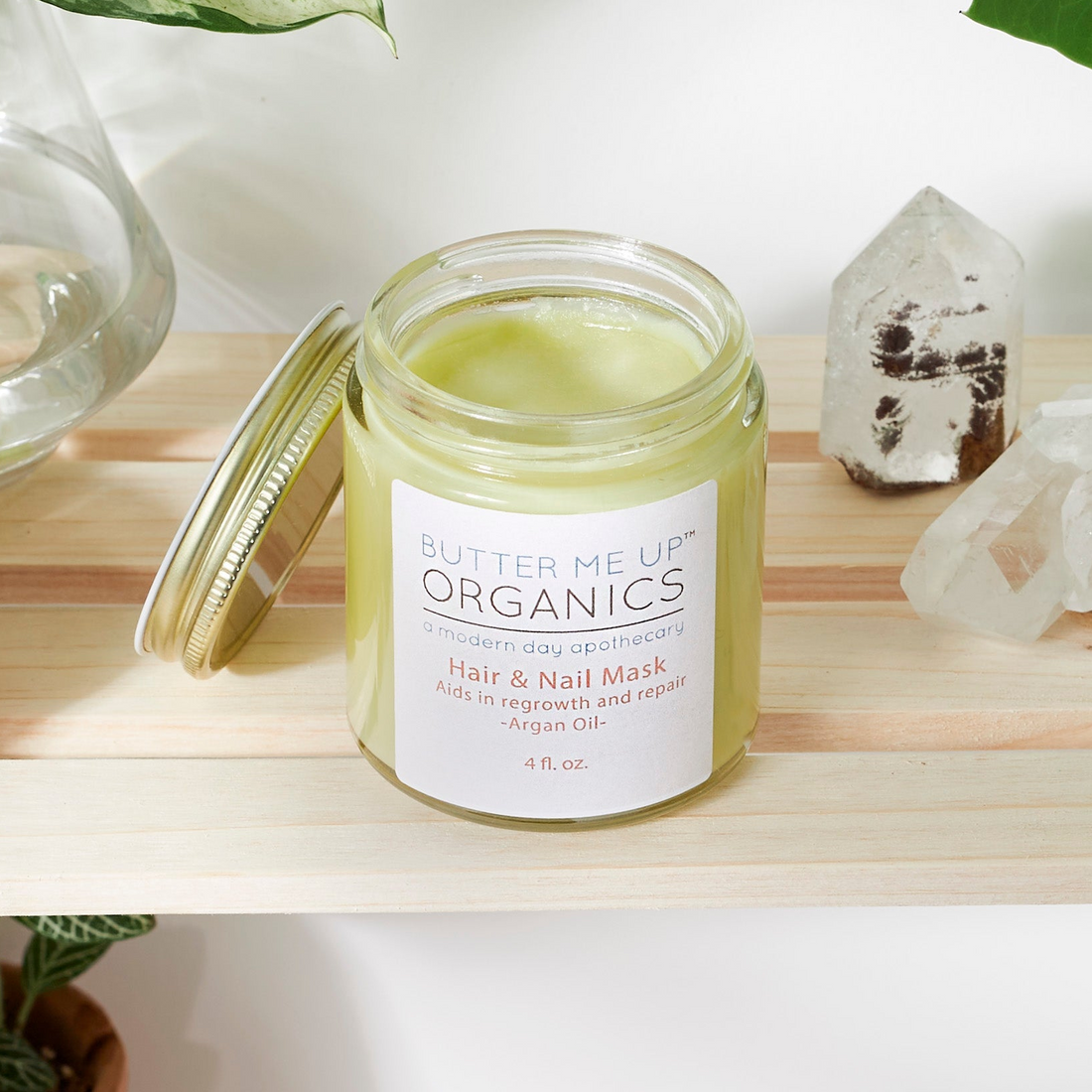 Jar of skincare product on a wooden shelf with plants and crystals