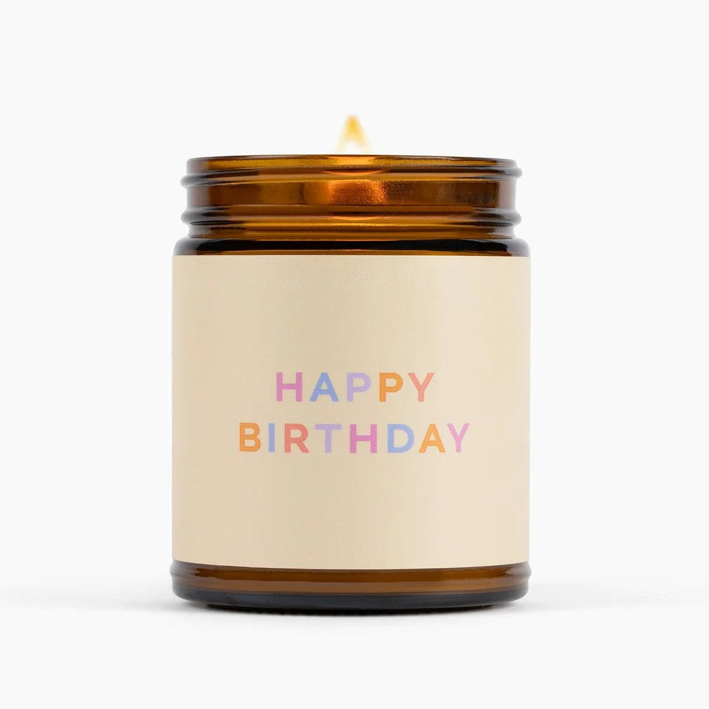 An amber glass jar candle with a cream-colored label that reads &