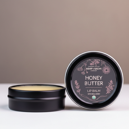 Honey Butter lip balm in a black tin with a dark background