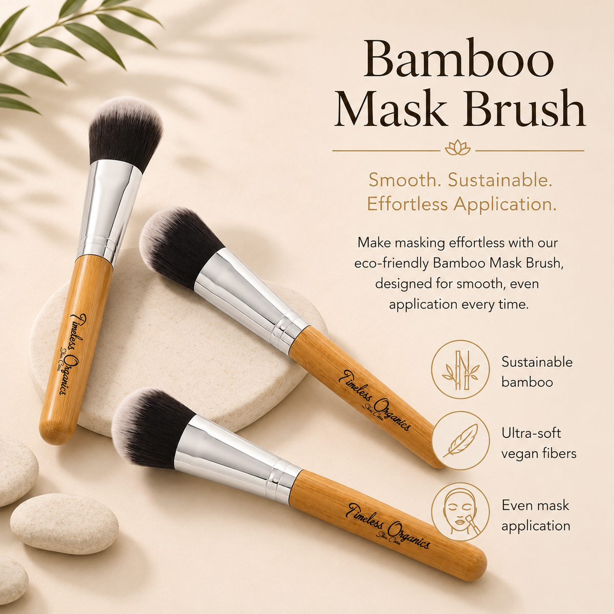 Three bamboo mask brushes with silver ferrules and black bristles, arranged on a beige surface with decorative stones and leaves. Text on the right reads &