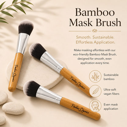 Three bamboo mask brushes with silver ferrules and black bristles, arranged on a beige surface with decorative stones and leaves. Text on the right reads &