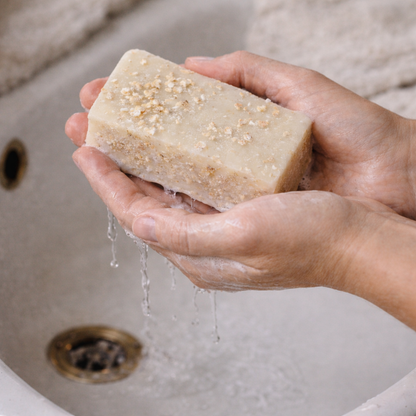 Hand holding a bar of soap over a sink