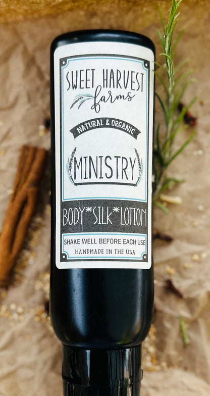 Black bottle of body silk lotion with a label on a natural background