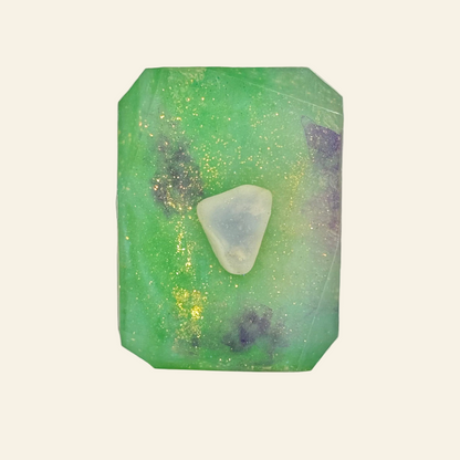 Green crystal with a triangular white stone on a reflective surface