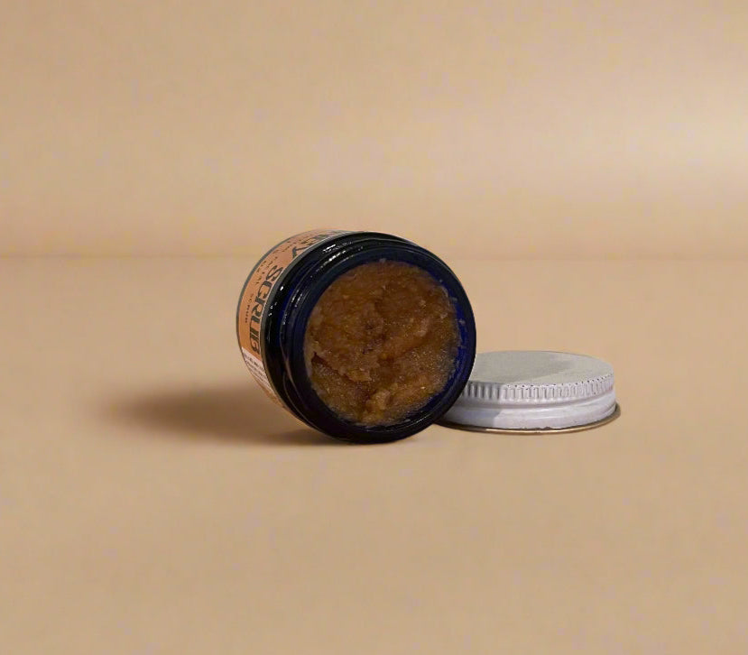Open jar of brown paste on a wooden surface with a white wall background