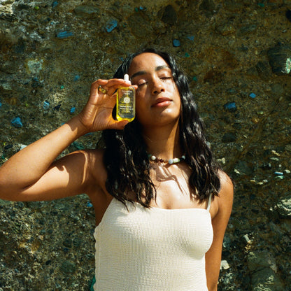 Woman holding a bottle of oil against a textured stone wall