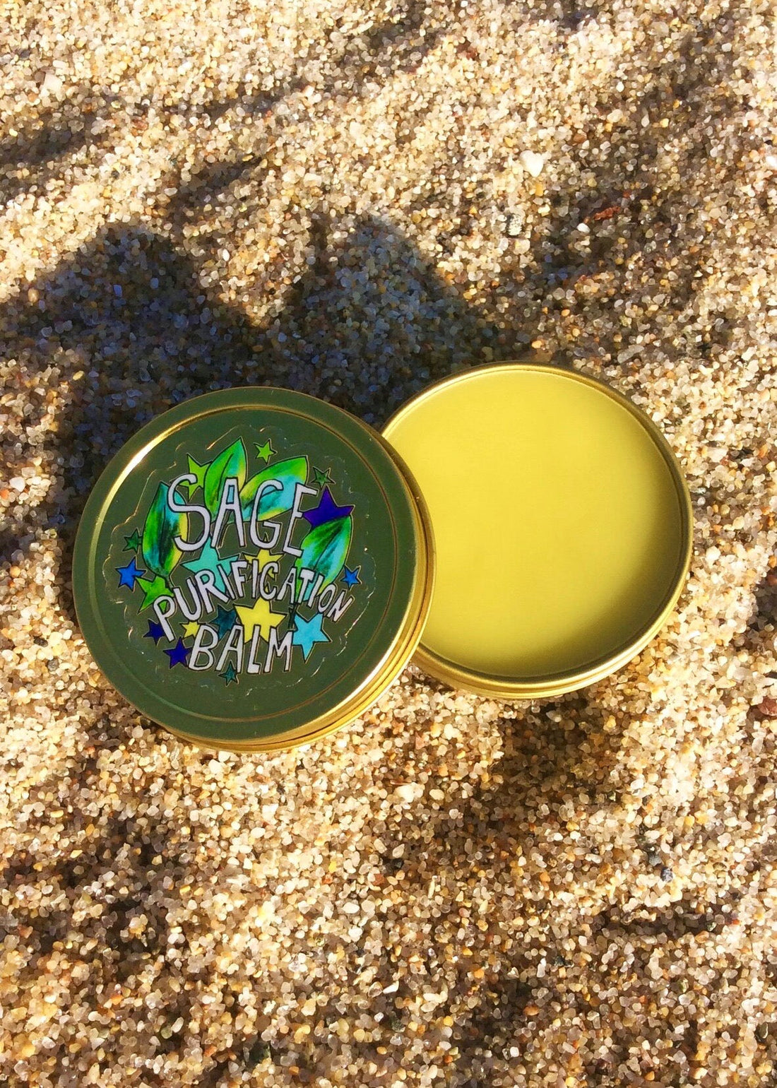 Sage Purification Balm container on a sandy surface