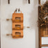 Wall-mounted leather bottle holder with three bottles on a white wall.