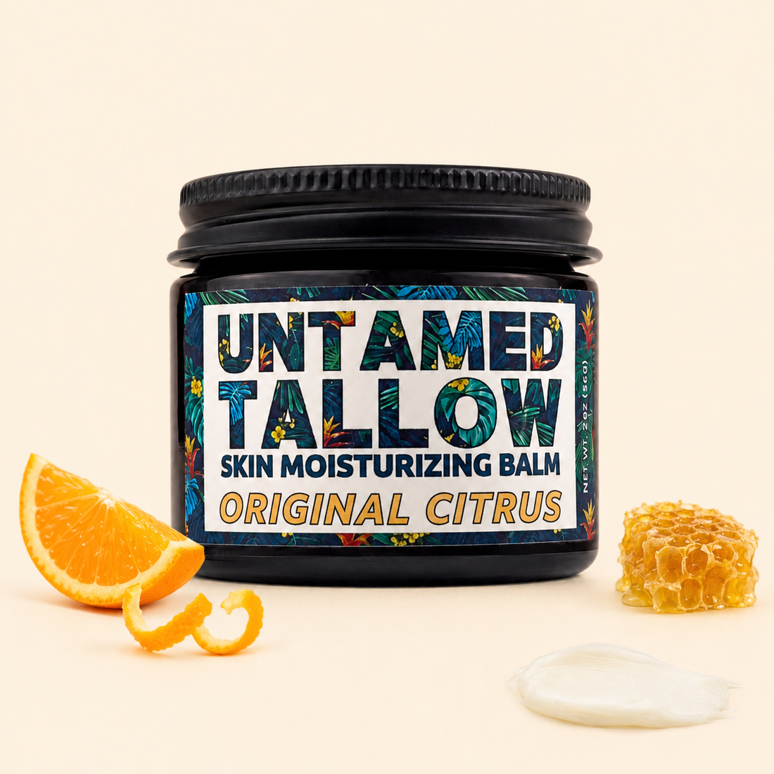 A jar of Untamed Tallow skin moisturizing balm in Original Citrus scent, styled with a citrus slice, peel, honeycomb, and a dollop of white balm on a warm cream background.