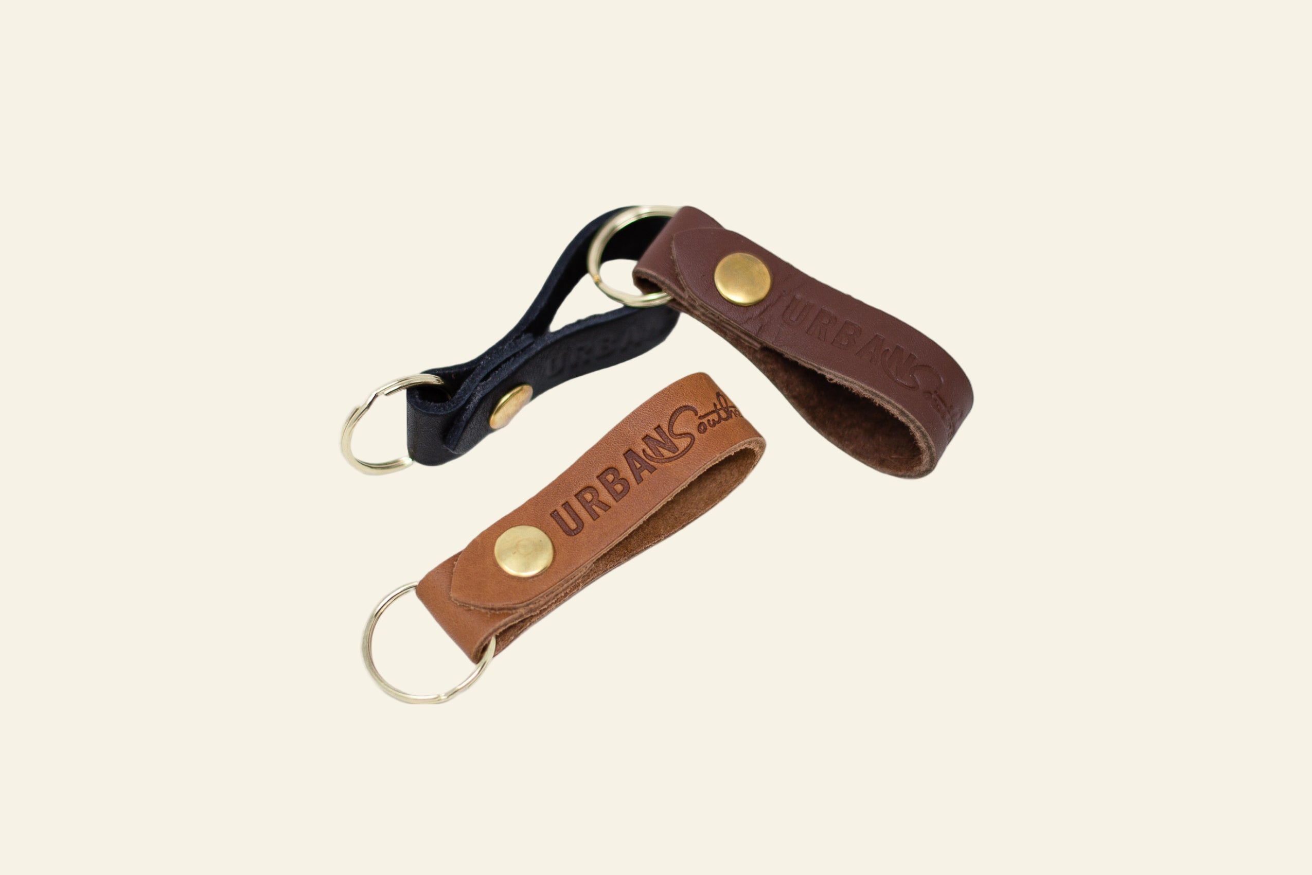 Two leather keychains, one brown and one black, on a white background.