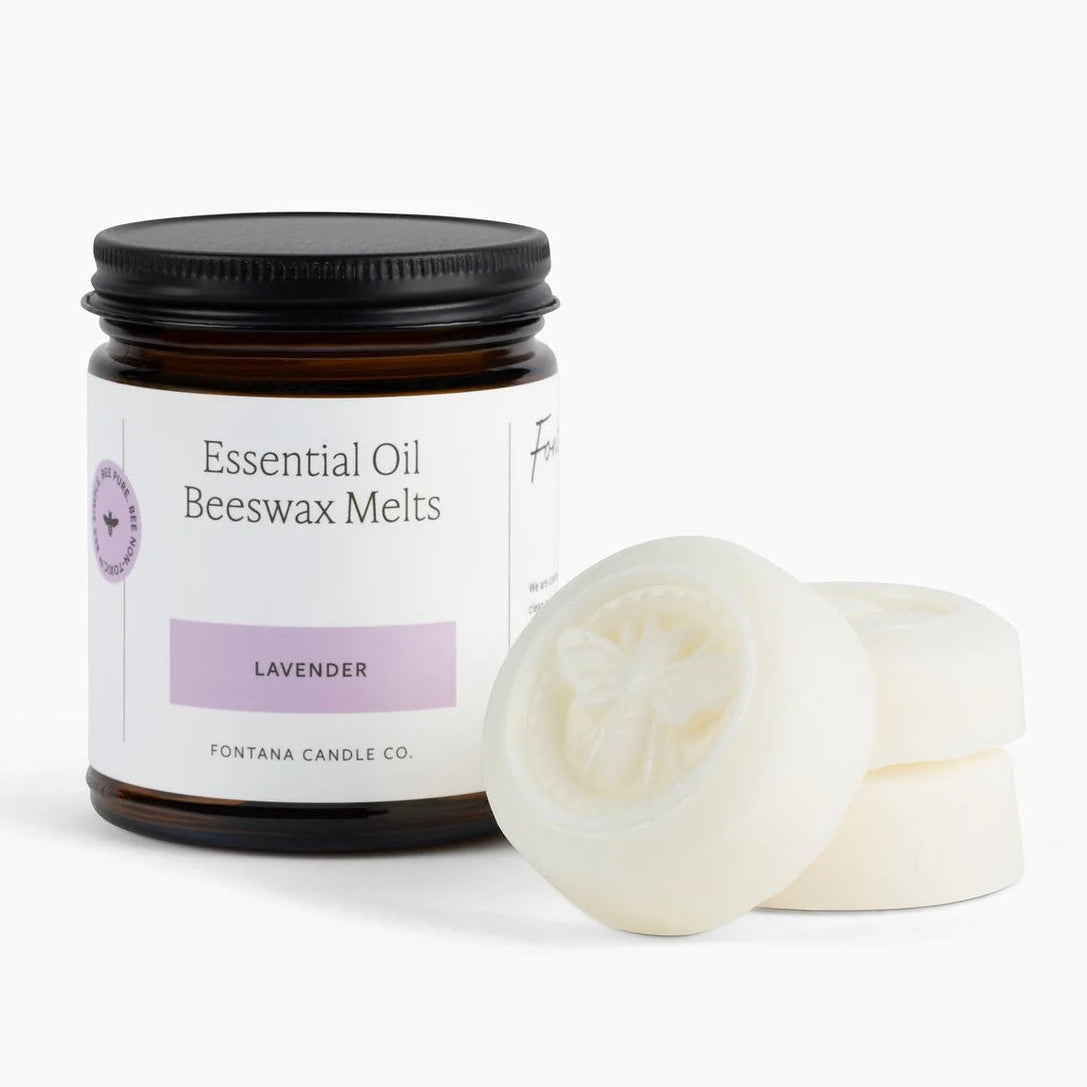 A jar of Fontana Candle Co. Essential Oil Beeswax Melts in the lavender scent, shown next to two round off-white wax melts on a clean white background.