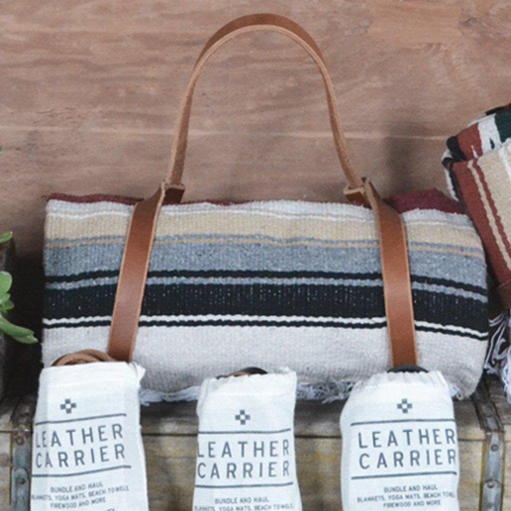Tote bag with leather straps, rolled blanket, and &