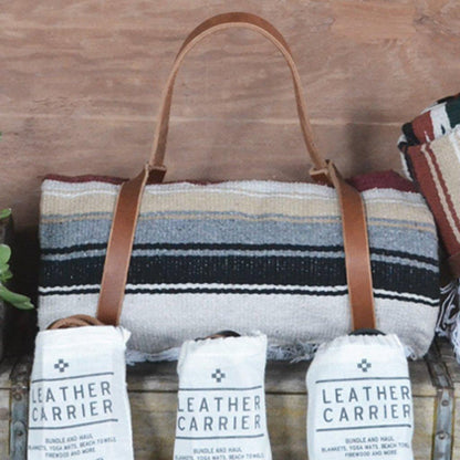 Tote bag with leather straps, rolled blanket, and &
