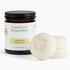Jar of essential oil beeswax melts with two melts on a white background