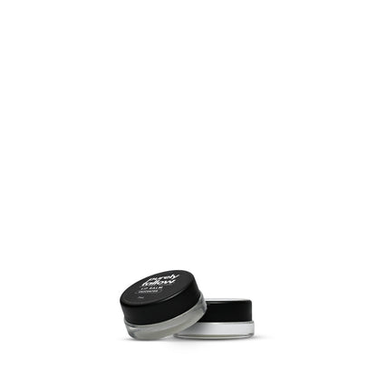 A small cosmetic jar with a black lid and clear container showing a white cream product inside, photographed on a plain white background.