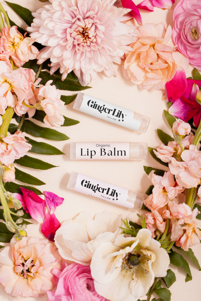 Ginger Lily lip balm surrounded by flowers on a light background