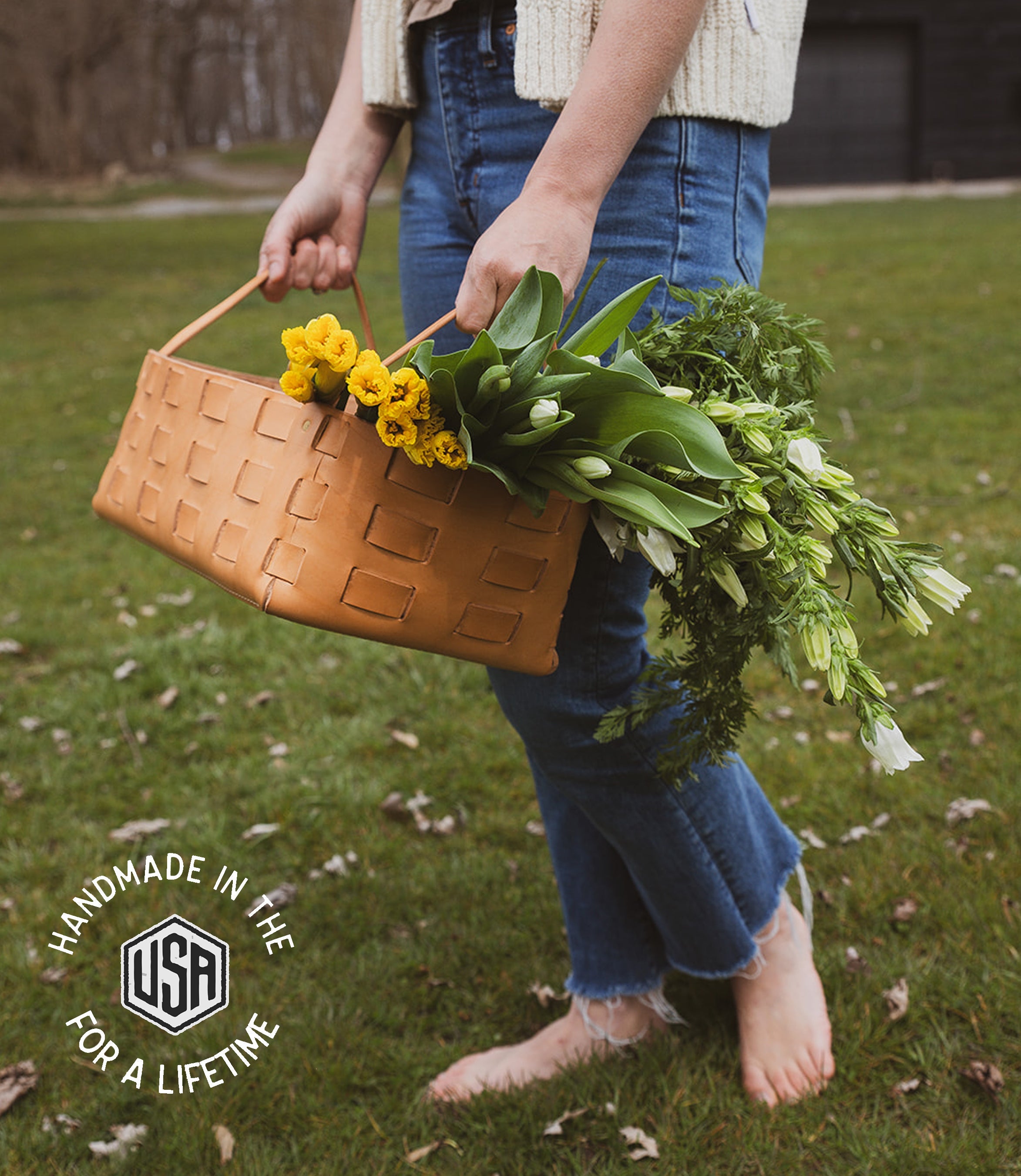 Person holding a woven basket with flowers outdoors, featuring &