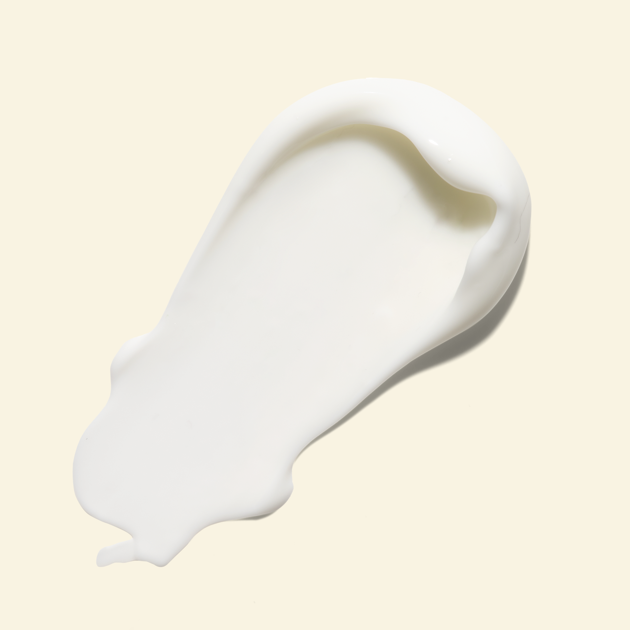A thick, creamy white product smear, likely a skincare cream or lotion, shown on a solid pale beige background.
