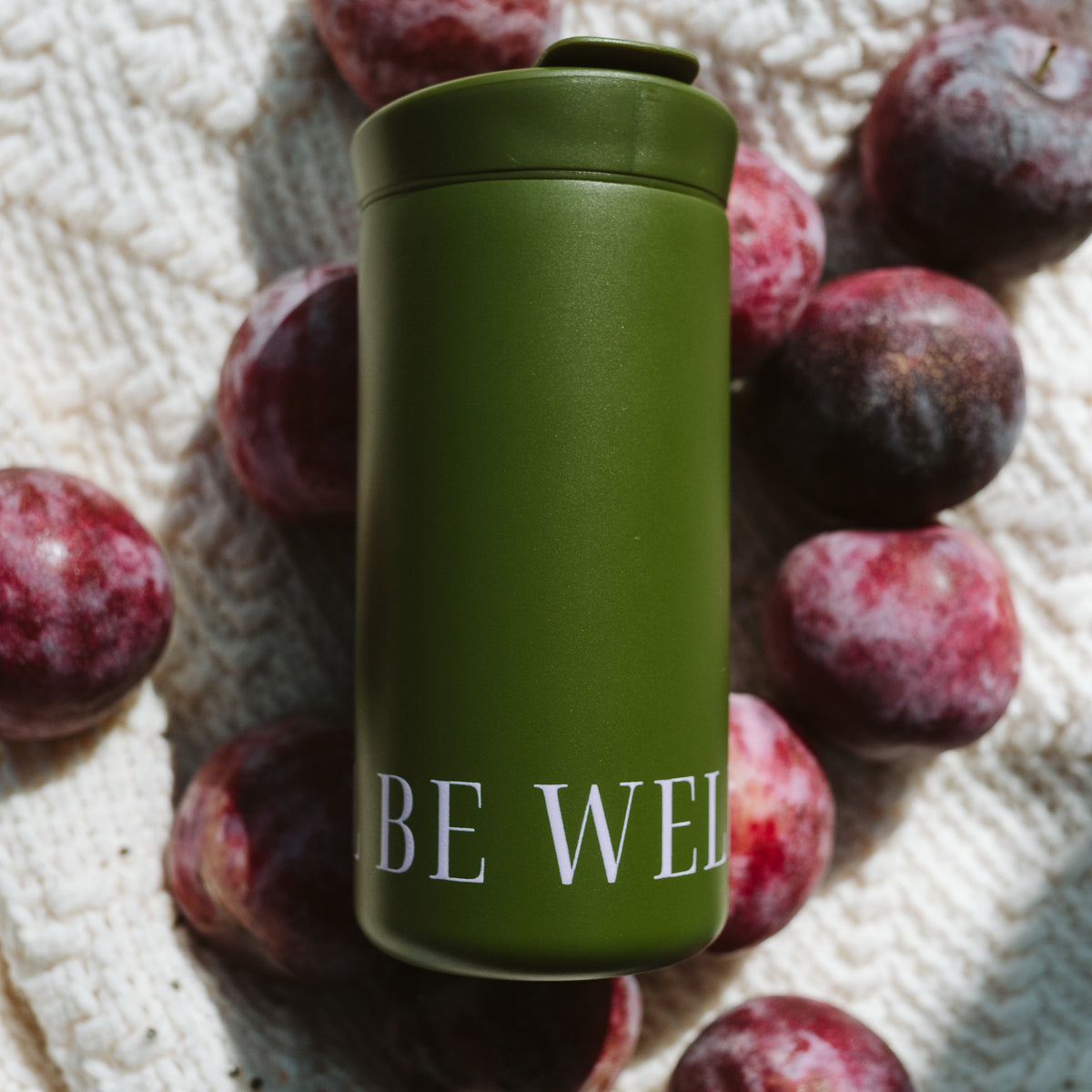 An olive green insulated tumbler with white text reading &
