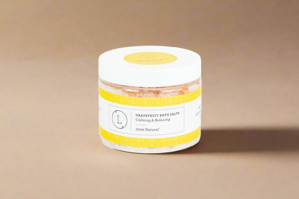Jar of grapefruit bath salts with a yellow label on a beige background