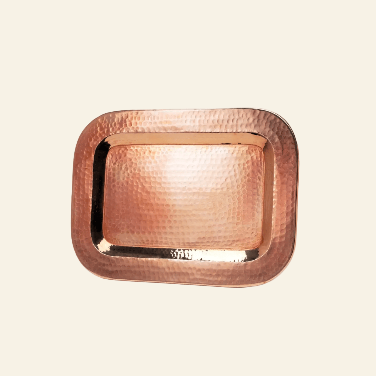 Copper tray with a textured border on a beige background