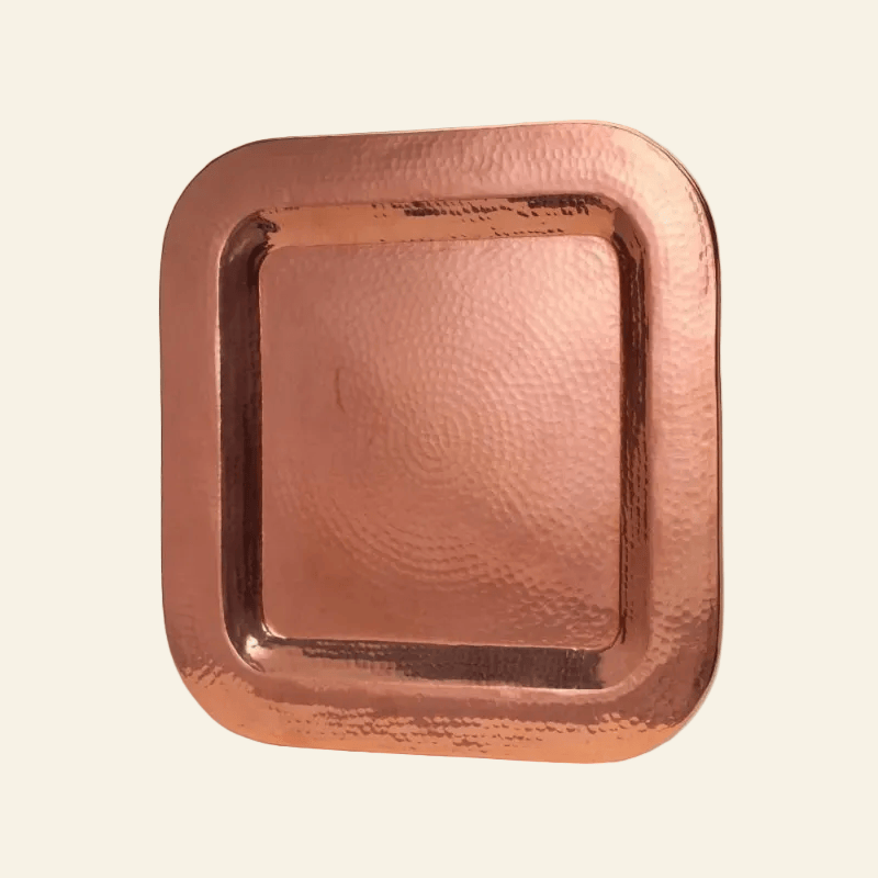 Copper tray with a textured surface on a light beige background