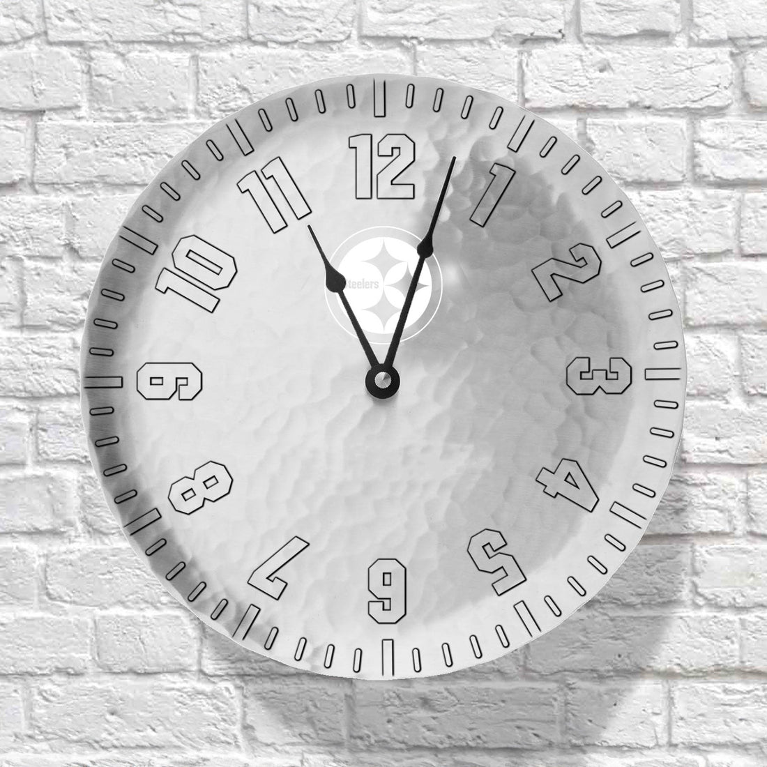 Round wall clock with black numbers and hands on a white brick wall background