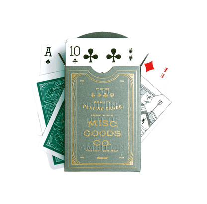 Playing cards with a green and gold packaging label, featuring the Misc. Goods Co. branding.