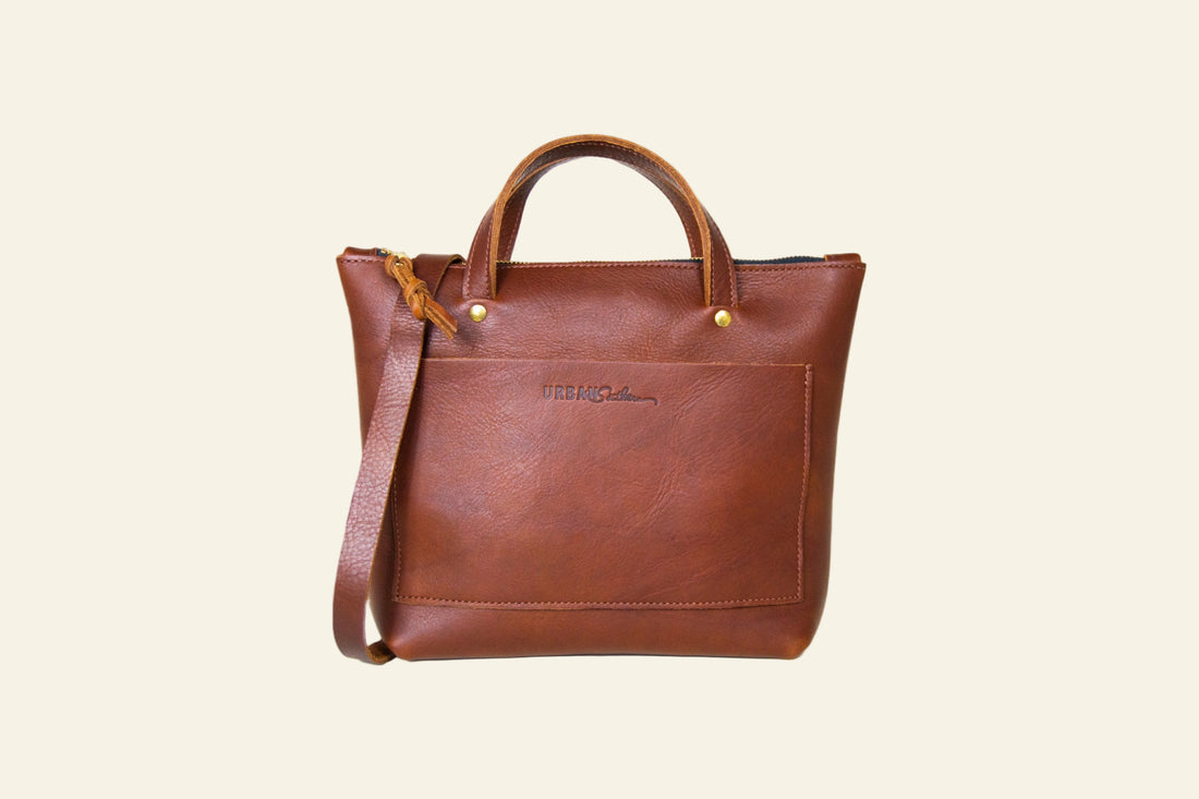Brown leather tote bag with a strap on a white background
